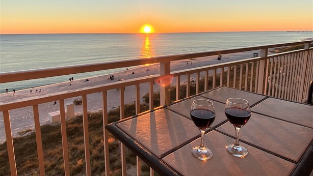 A balcony with two wine glasses and a view of the sunset over the ocean. -  Spectacular 5th floor Direct Oceanfront - lots of amenities!!- sleeps up to 7 (Panama City Beach)