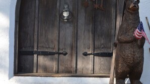 A wooden door with a bear statue and an American flag, and a sign that reads "Gone Skiing." - Unique & charming home with stunning view of Mt Washington. Pet friendly. (Jackson)