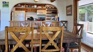 A rustic kitchen with wooden cabinets, a dining table with chairs, and a hanging light fixture. - Unique & charming home with stunning view of Mt Washington. Pet friendly. (Jackson)