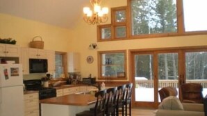 A spacious kitchen with a central island, wooden cabinets, and a large window offering a view of trees. - Stratton, Okemo, Bromley, Viking Nordic XC, Skiing!! (Londonderry)