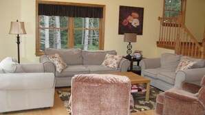 A living room with a sofa, armchairs, a coffee table, and a lamp. There is a window with a view of trees and a painting on the wall. - Stratton, Okemo, Bromley, Viking Nordic XC, Skiing!! (Londonderry)