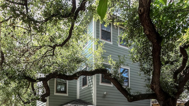 A two-story house with a porch, a wooden fence, and a large tree providing shade. - Downtown oasis, walking distance to Capitol, UT, Zilker Park, music venues (Austin)