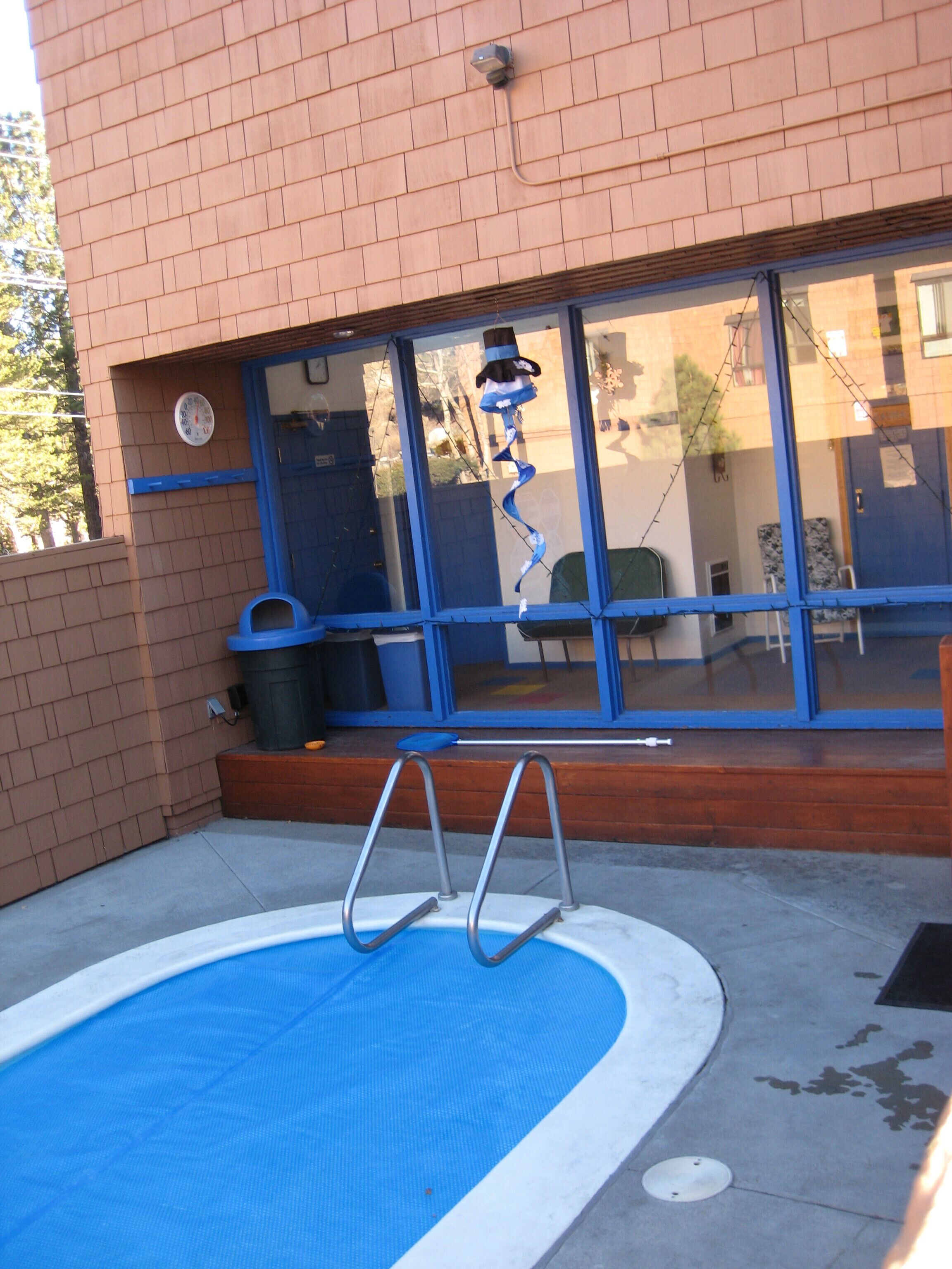 Une piscine avec un escalier, une poubelle et une porte bleue.