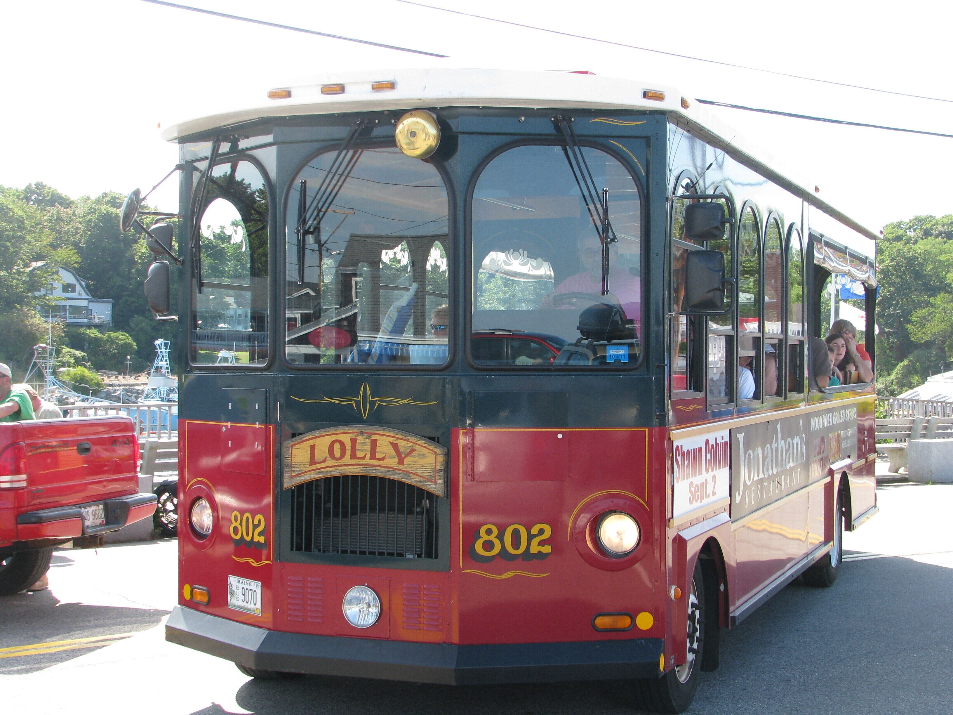 A vintage red and black bus with the number 802 and the name "LOLLY" on the front.