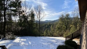 Paisaje nevado con una terraza de madera y vistas a un área boscosa.