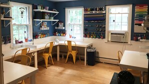 Ein Zimmer mit einem weißen Schreibtisch, gelben Stühlen und Regalen mit verschiedenen Gegenständen.