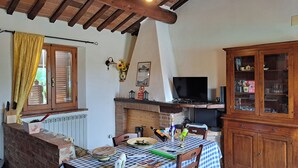 A dining area with a checkered tablecloth, wooden chairs, a brick fireplace, and a television. - Villino Cortona - Holiday home with private pool, wifi, a/c - Tuscany (Cortona)