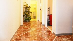 A hallway with a tiled floor, a potted plant, and a bed in the background. - Anthony's Home 5 people (Roma)