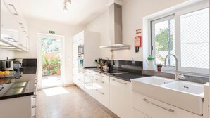 A modern kitchen with white cabinets, a black countertop, and a window with a view of greenery. - Family Villa in LISBON,heated pool,elevator,parking,6 bedrooms,sleeps 14 (Lisboa)