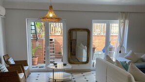 A living room with a white sofa, a wicker chair, a round table, and a large mirror. There is a patterned floor and a ceiling light fixture. - Family Villa in LISBON,heated pool,elevator,parking,6 bedrooms,sleeps 14 (Lisboa)