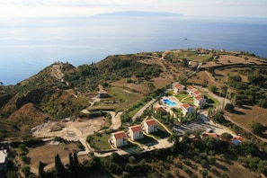 Houses cluster around a central courtyard, nestled on a hillside with a view of the sea.