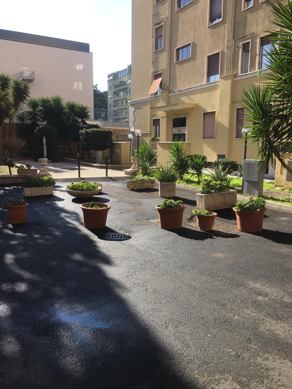 Une cour intérieure agrémentée de plantes en pot, d’une statue et d’un bâtiment doté de nombreuses fenêtres.