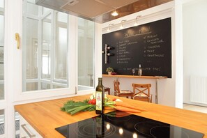Una cocina con una pizarra mostrando opciones de vino, una botella de aceite de oliva y verduras frescas sobre la encimera.