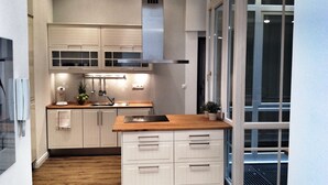 A modern kitchen with white cabinetry, a wooden countertop, and a built-in stove. - Grandiose 3BR § 3BathR apt, middle of downtown. Back and better than ever! (Budapest)