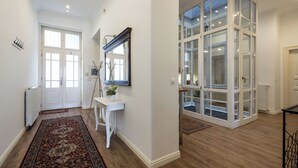 A hallway with a white console table, a mirror, and a red rug. - Grandiose 3BR § 3BathR apt, middle of downtown. Back and better than ever! (Budapest)