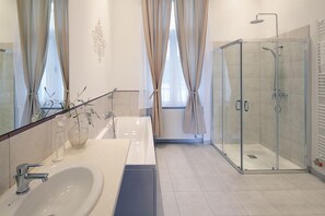 Un baño moderno con ducha de mampara de vidrio, un lavamanos grande y un espejo.