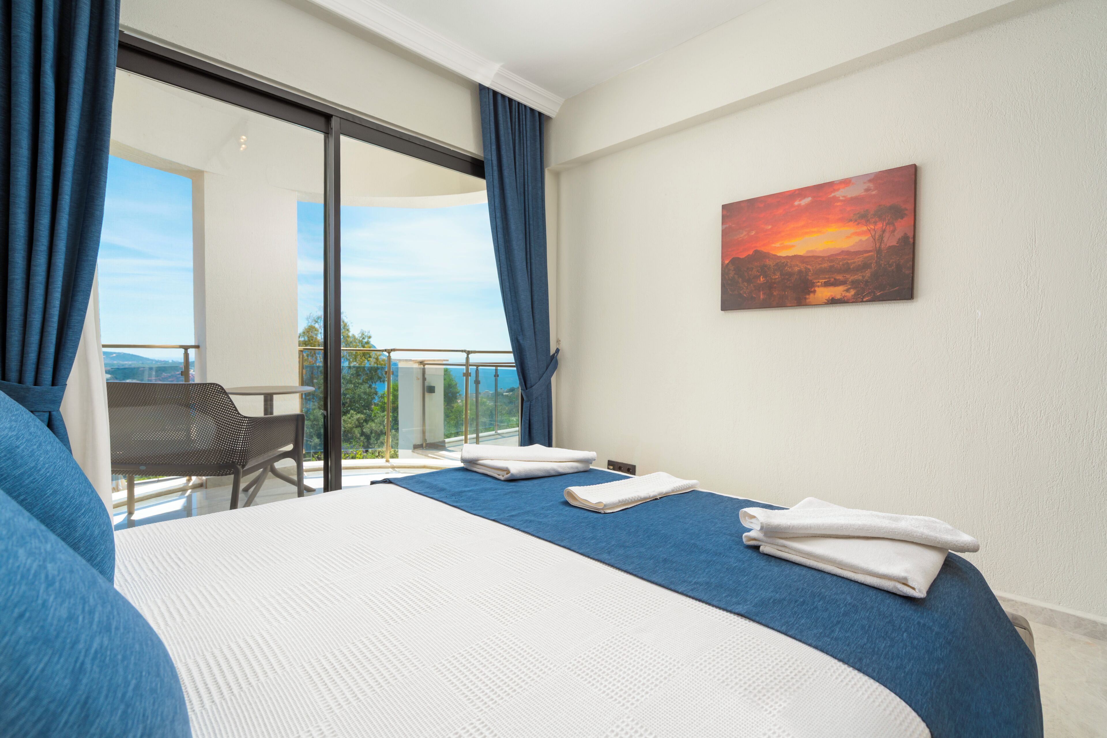 Een hotelkamer met een bed, een schilderij en uitzicht op het landschap.