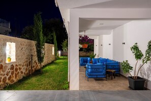 An outdoor seating area with blue furniture, a stone wall, and a potted plant.