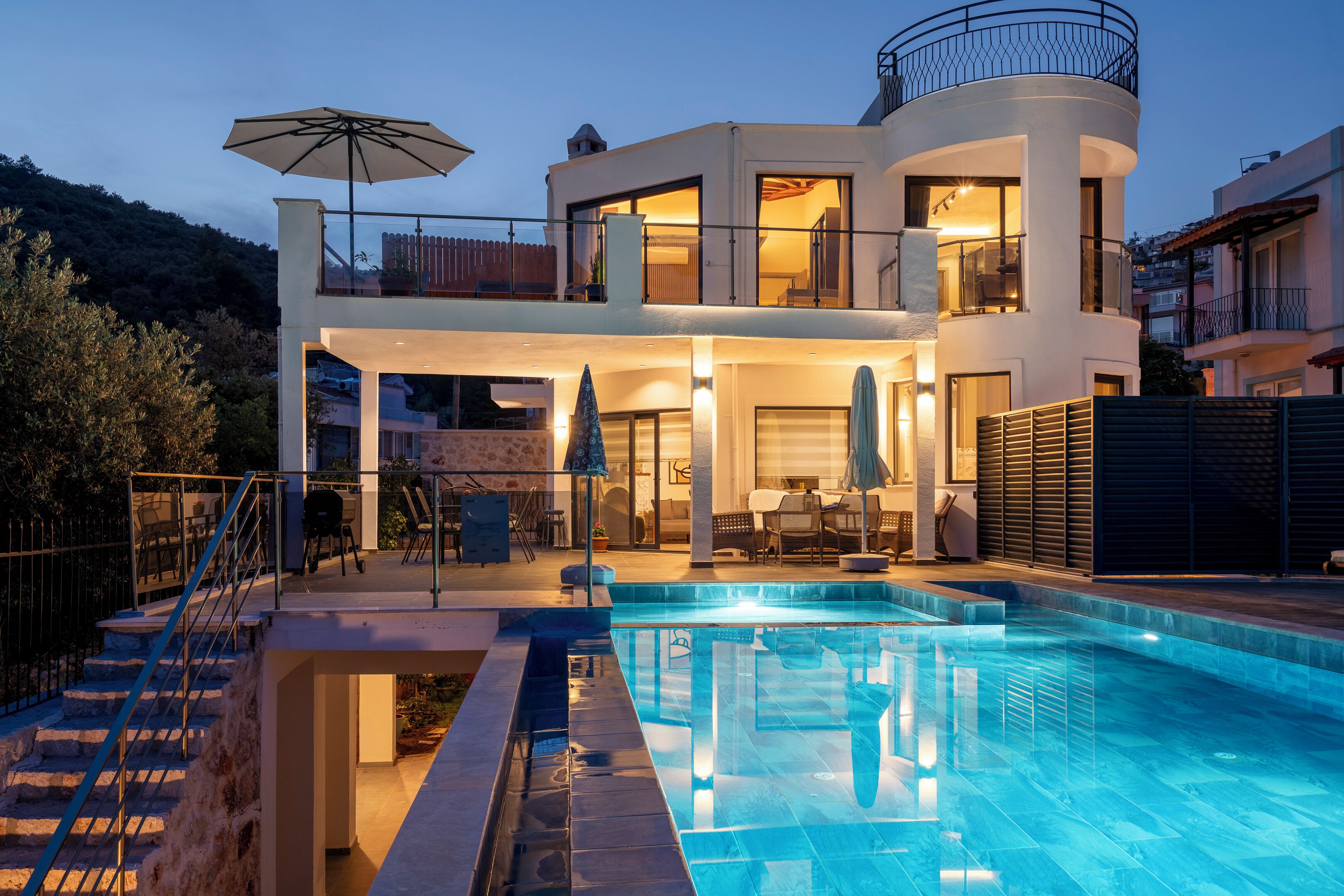 Une maison moderne à deux étages, dotée d’une piscine, de mobilier d’extérieur et d’un balcon.