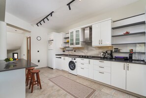 A modern kitchen with white cabinetry, a built-in washing machine, and a coffee maker.