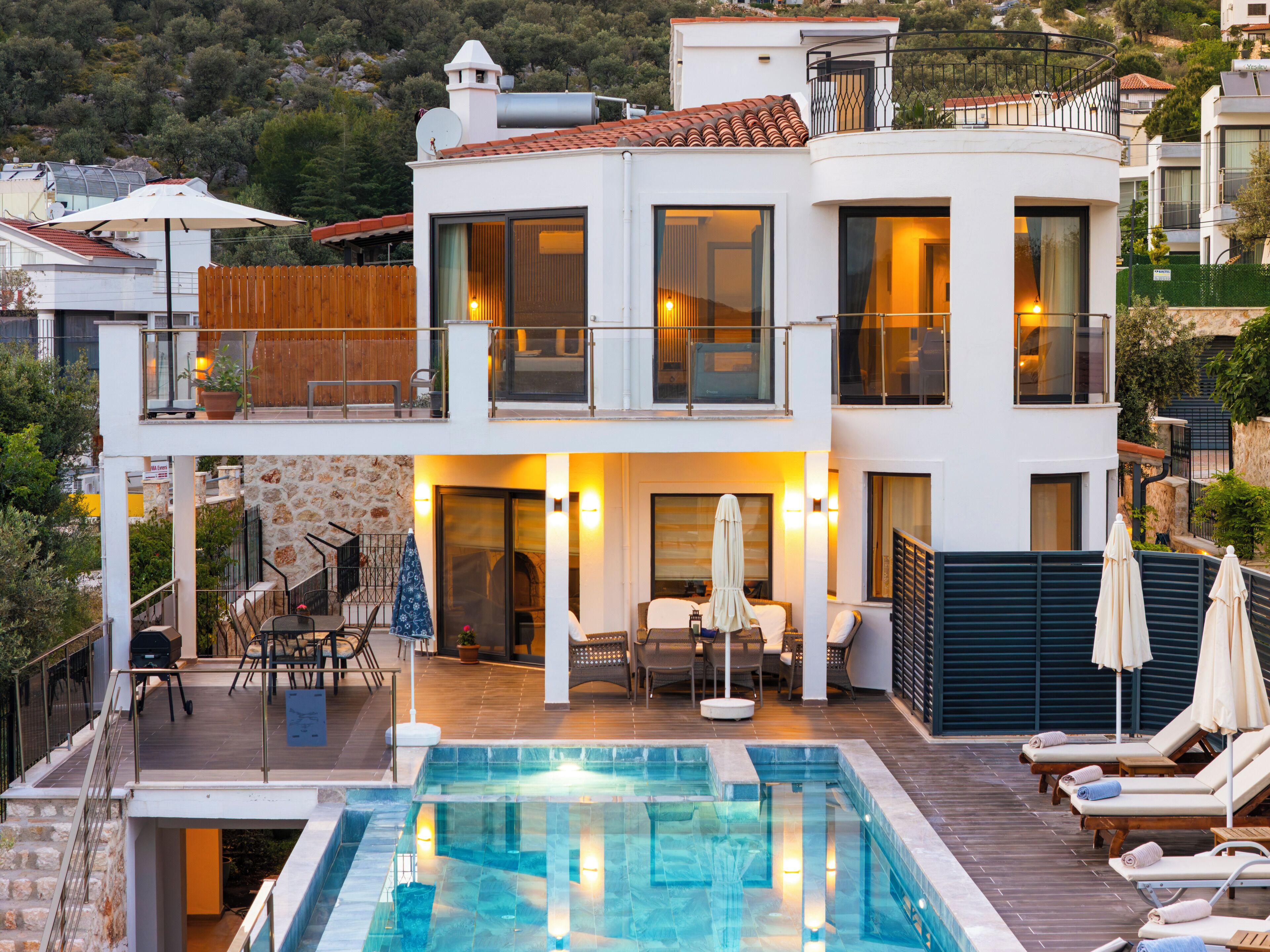 Una casa moderna de dues plantes amb piscina, seients exteriors i un balcó.
