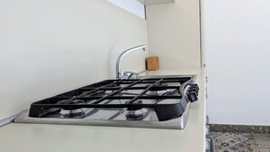 Una cocina con estufa a gas, un fregadero y un bloque de madera.