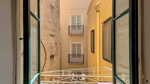 Un estrecho callejón con dos balcones, uno con baranda metálica y otro con una puerta blanca.