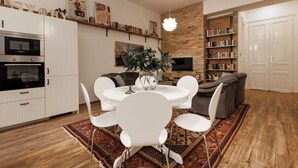 Una sala de estar moderna con una mesa de comedor, sillas blancas, un sofá gris y una estantería.