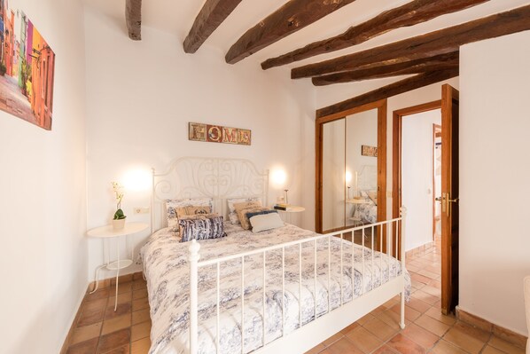 A bedroom with a bed, bedside tables, a mirror, and a door.