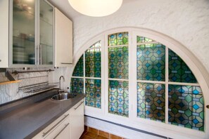 Enjoy cooking in this kitchen with a beautiful arched window, stainless steel sink, and ample countertop space.
