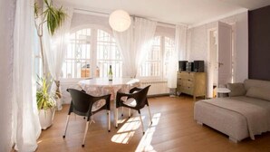 Una habitación luminosa con una mesa de comedor, sillas, un sofá y una planta en maceta.