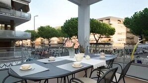 An outdoor dining area with tables and chairs, a large pillar, and a view of the cityscape. - GREGORY BIG FAMILY (Roma)