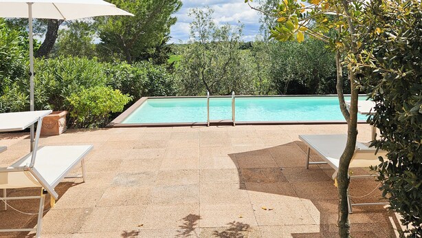 Área de piscina com espreguiçadeiras e um pergolado.