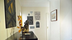Un couloir avec un comptoir d’accueil noir, une sculpture et plusieurs œuvres d’art murales à caractère motivant.