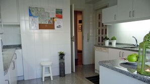 Une cuisine moderne avec des meubles blancs, un plan de travail en granit et un petit tabouret.