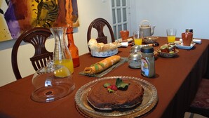 Une table à manger dressée avec des aliments pour le petit-déjeuner, notamment un gâteau, du pain et des boissons.
