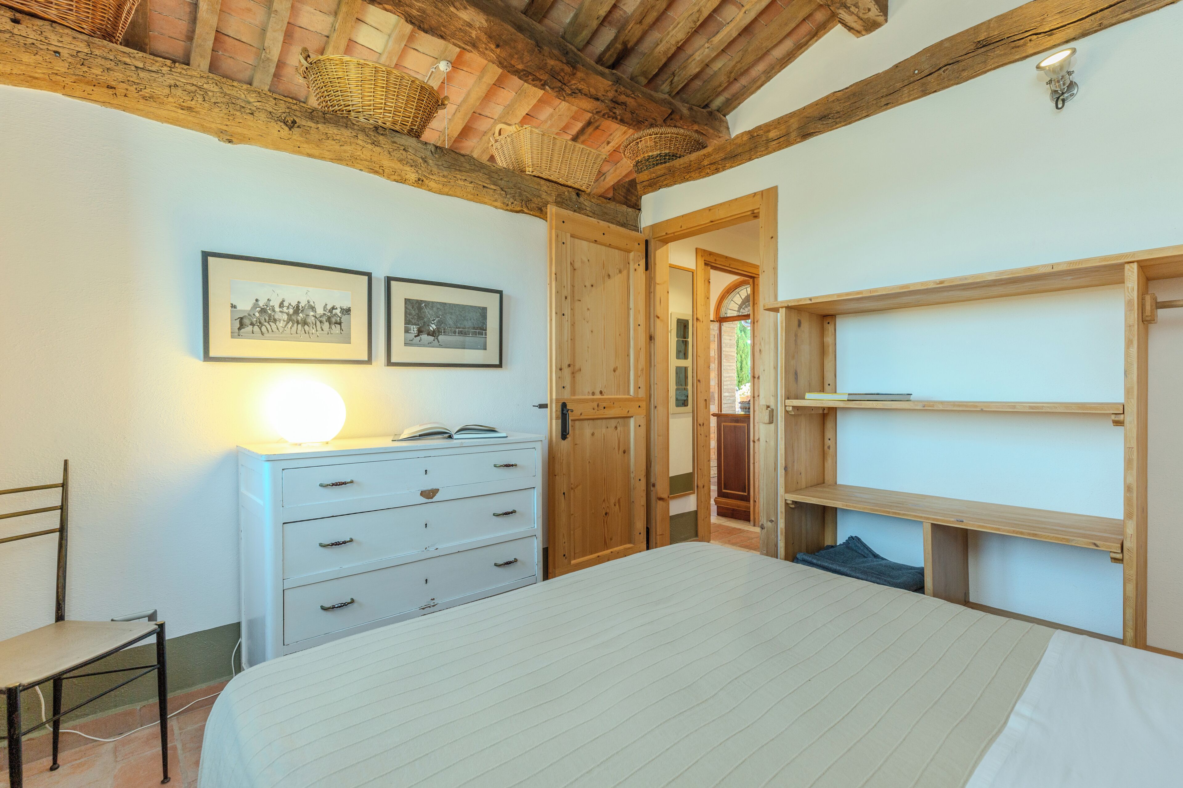 Une chambre à coucher avec un lit, une commode, une chaise et des étagères en bois.