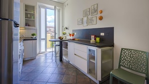 A modern kitchen with a built-in oven, a refrigerator, and a sink. There is a dining area with a table and chairs, and a small refrigerator. The kitchen has a window that lets in natural light. - THE 4th FLOOR  2 bedrooms + Free Parking near the centre (Firenze)
