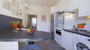A modern kitchen with a built-in oven, a washing machine, and a dining area with a table and chairs. - THE 4th FLOOR  2 bedrooms + Free Parking near the centre (Firenze)