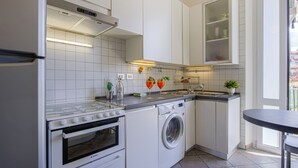 A compact kitchen with a stove, oven, washing machine, and a sink. - THE 4th FLOOR  2 bedrooms + Free Parking near the centre (Firenze)