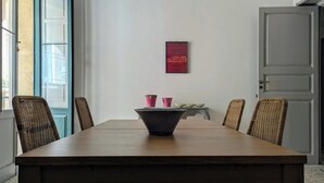 A dining area with a wooden table, wicker chairs, and a framed artwork on the wall.