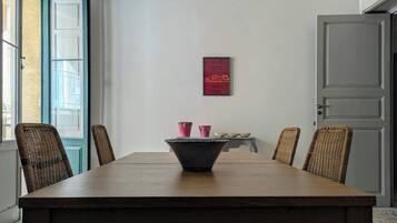 Ein Essbereich mit Holztisch, Korbstühlen und einem gerahmten Kunstwerk an der Wand.