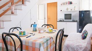 A compact kitchen with a wooden staircase, a dining table set with plates, a kettle, and a bowl. - HOUSE OF THE DUNES - DONNALUCATA (Donnalucata)