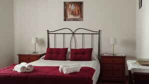 A neatly made bed with red and white bedding, two bedside tables with lamps, a wooden nightstand, and a framed picture on the wall. - Cottage on a quiet place, ideal for rest (Fuencaliente de La Palma)