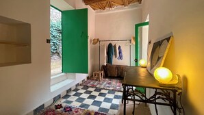 A narrow hallway with a checkered floor, a green door, and a rustic ceiling.