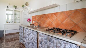 Una cocina con estufa a gas, armarios blancos y salpicadero de azulejos.