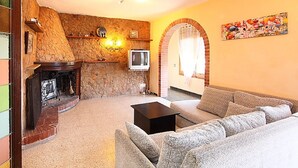 Una sala de estar con chimenea de piedra, un televisor y un mural colorido en la pared.