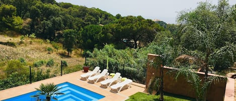 A swimming pool with lounge chairs, surrounded by a well-maintained lawn and trees.