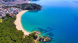 An aerial view of a coastal area with a beach, buildings, and a forested area. - Holiday Home, Private Pool, sea views, Costa Brava. (Lloret de Mar)
