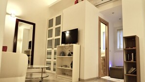 A modern living room with a flat-screen TV, a white sofa, a coffee table, and a bookshelf. - Quiet luxury apartment in the middle of Rome historical center. (Roma)